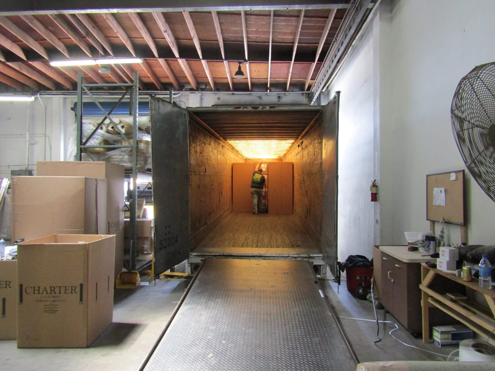 A shipping container backed up to the loading dock, with cartons beside it
