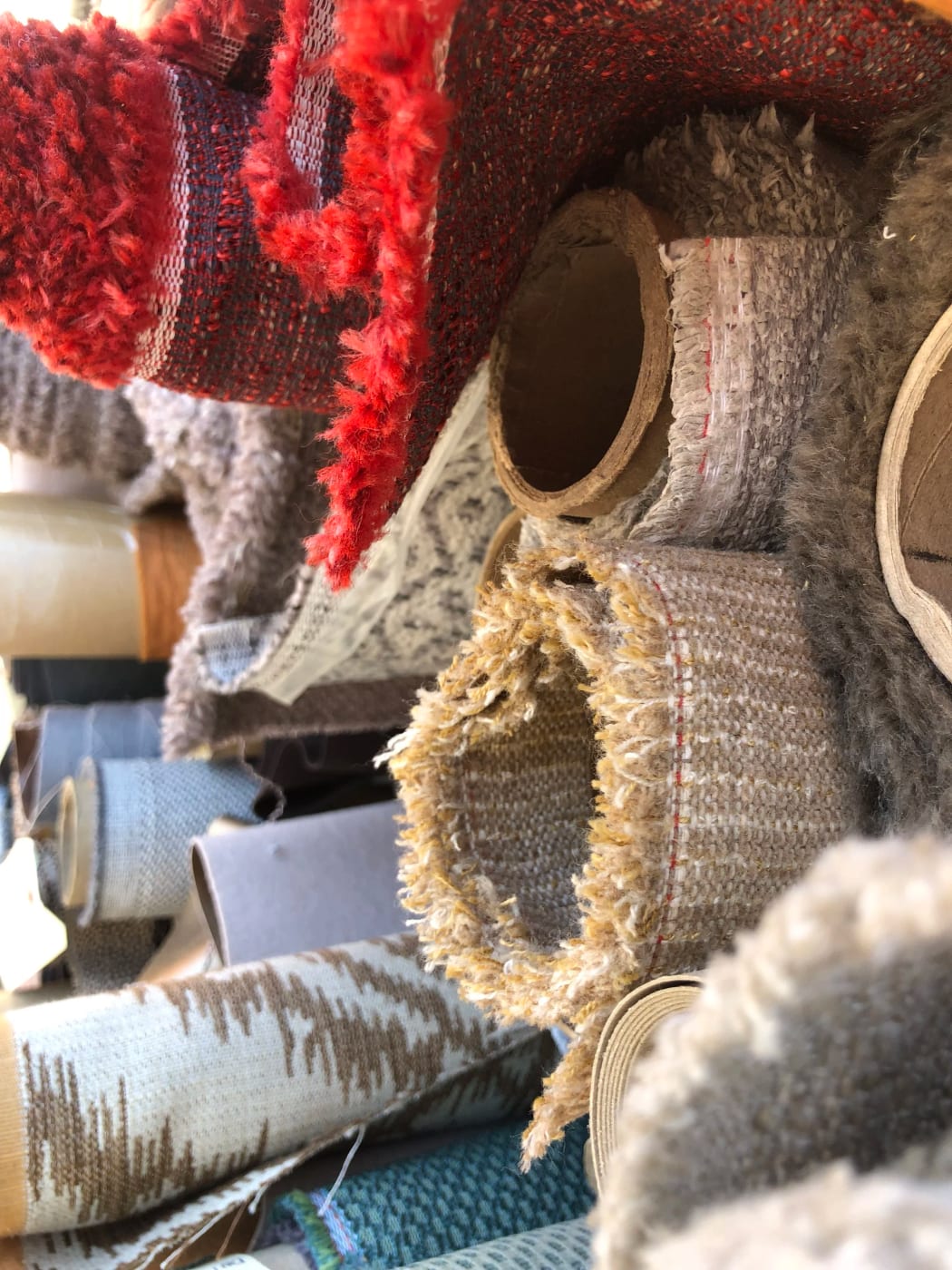 Rolls of upholstery fabric in reds, creams and grays