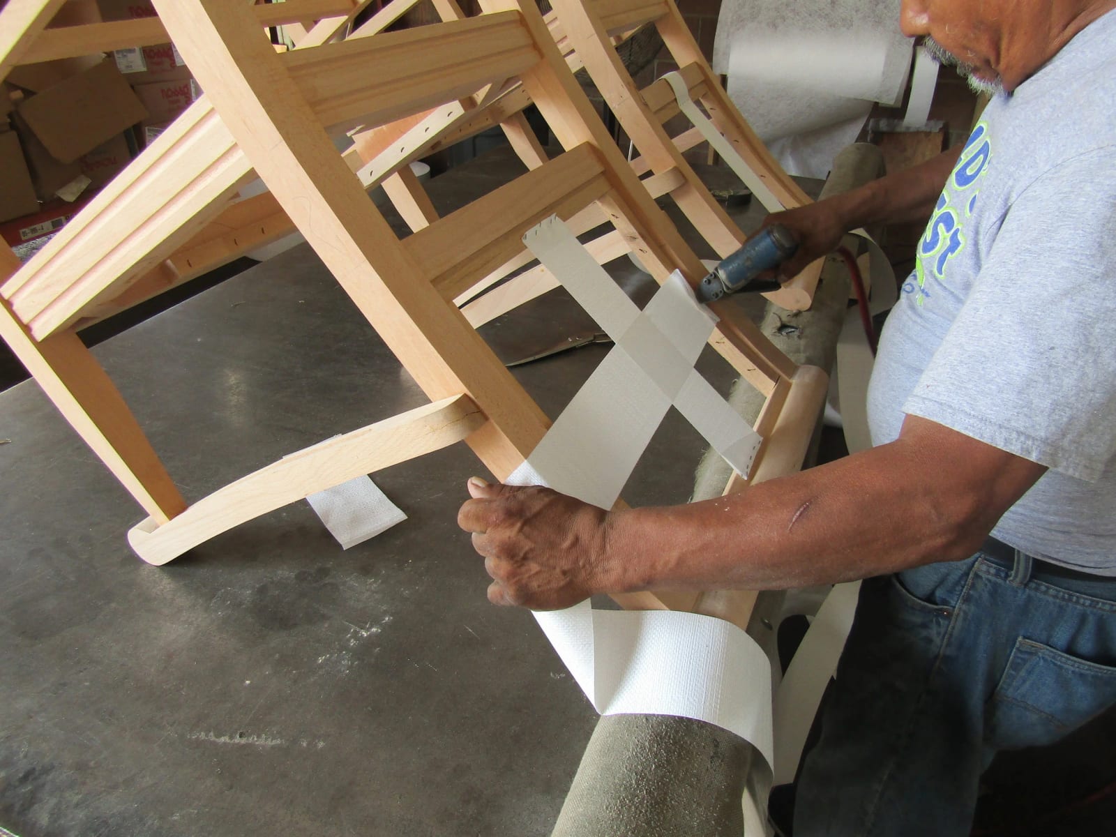 Webbing being pulled tight across a bare wooden chair frame