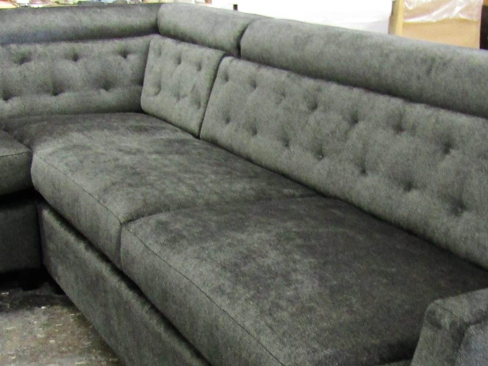 A gray sectional with a button-tufted back