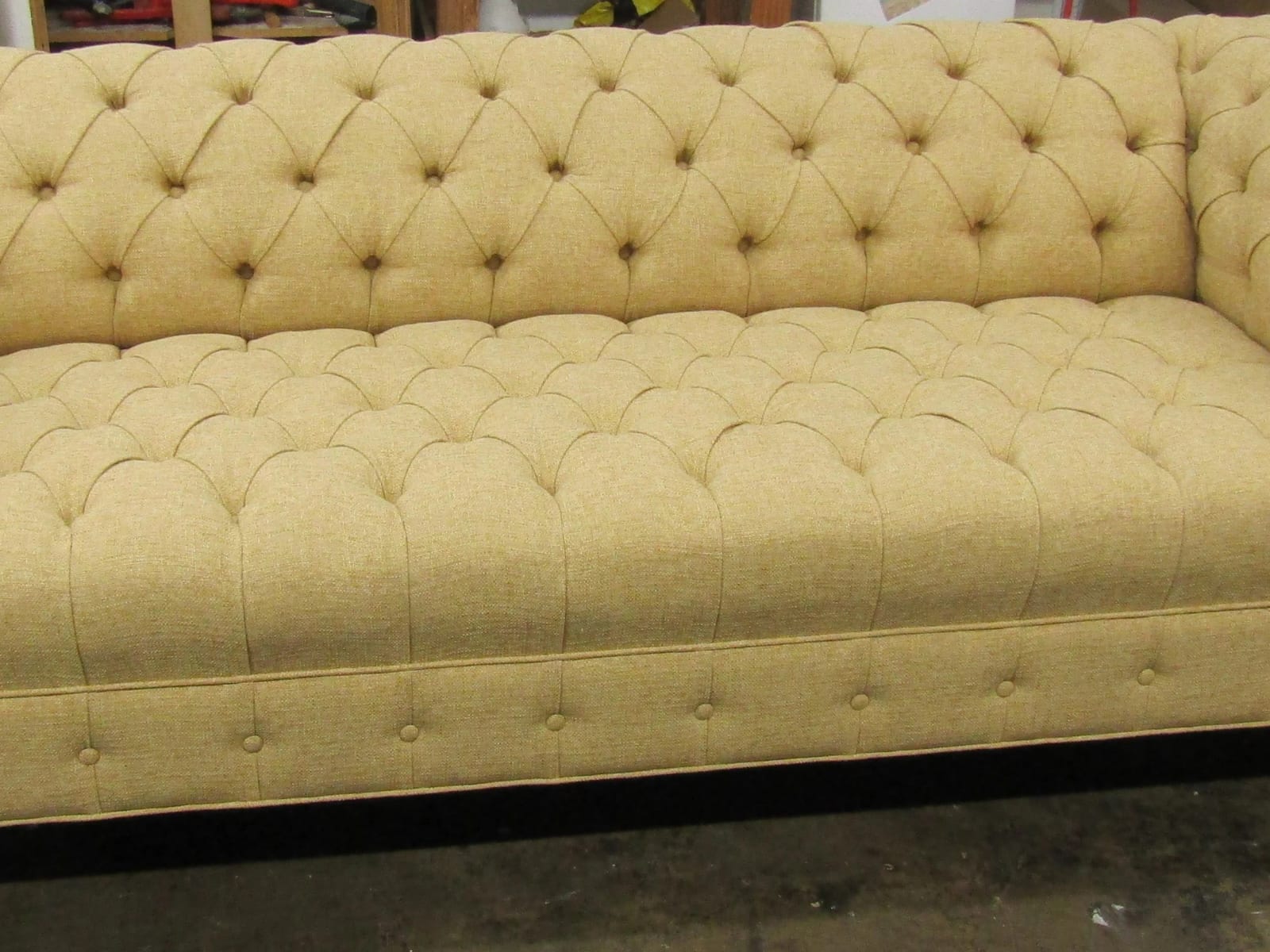 A button-tufted sofa in a pale gold fabric