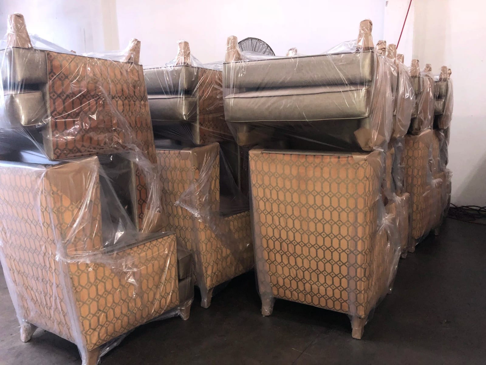 Finished upholstered chairs wrapped in plastic and stacked